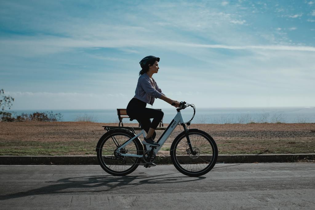 Fahrradfahrer fährt einsam über eine Straße, Naturkulisse im HIntergrund