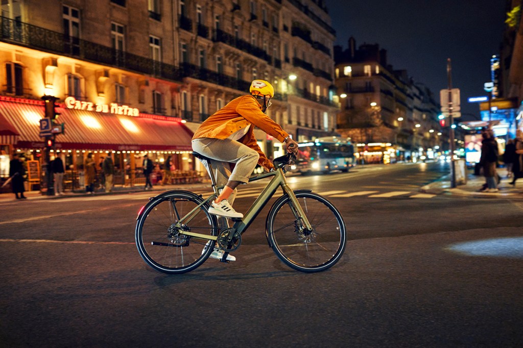 Mann fährt auf einem E-Bike nachts durch die Stadt