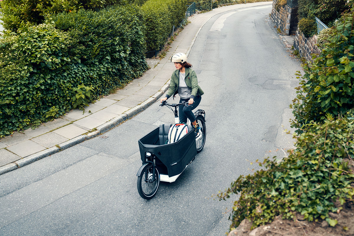 Frau fährt mit Riese & Müller Packstar 70 E-Cargo-Bike über Radweg