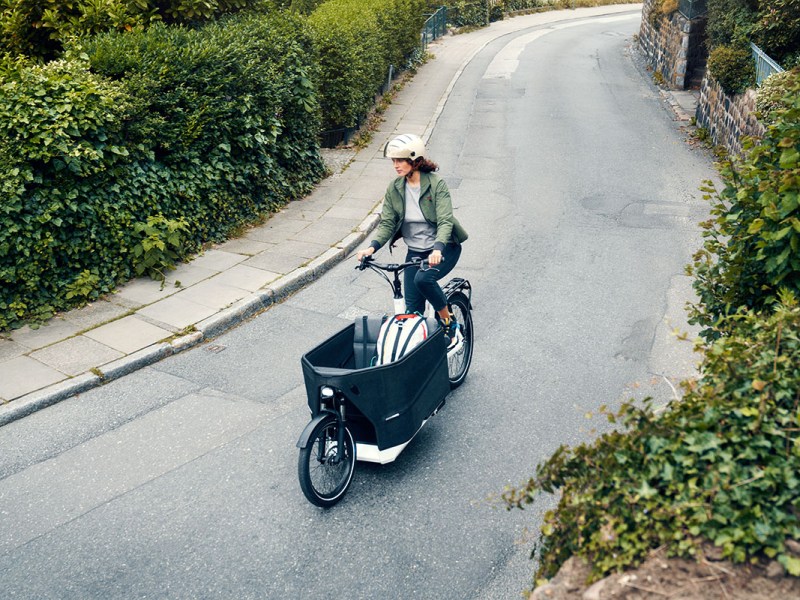 Frau fährt mit Riese & Müller Packstar 70 E-Cargo-Bike über Radweg