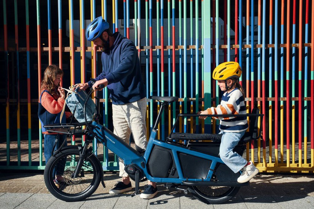 Mann und zwei Kinder mit E-Cargo-Bike Multitinker von Riese & Müller vor Hauswand