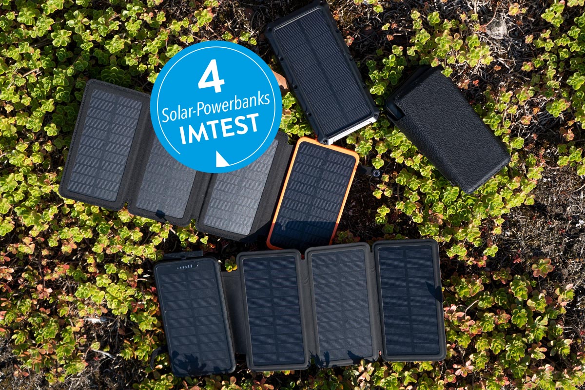 Vier Solar-Powerbanks auf einer Wiese liegend.