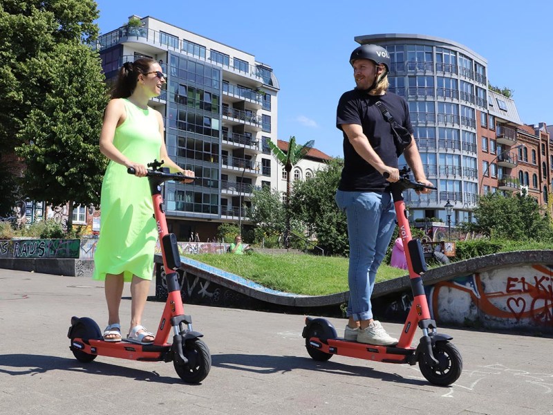 Zwei Menschen draußen auf E-Scooter fahrend.