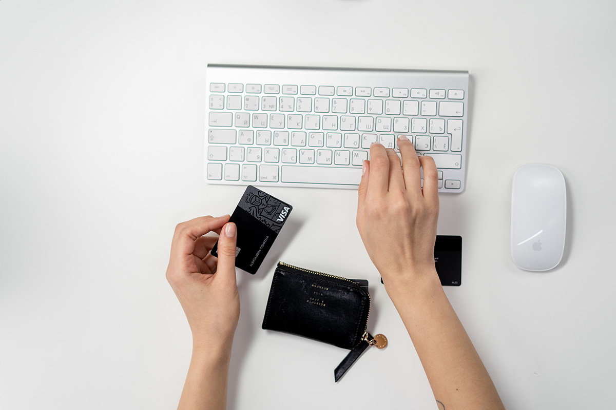 Eine Tastatur mit Händen und einer Kreditkarte.