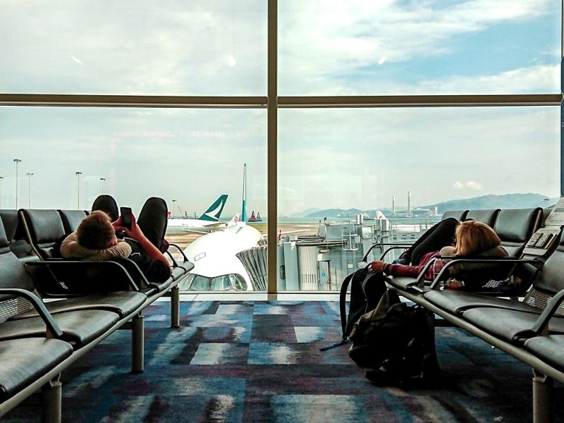 Zwei Menschen liegen auf Bänken im Flughafen