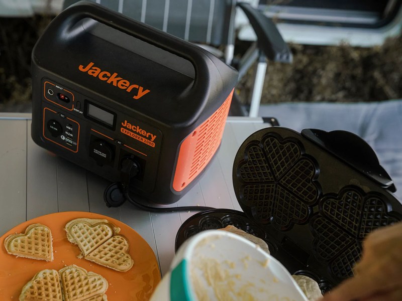 Es ist ein Tisch mit Waffeleisen und Waffel zu sehen. Außerdem die Jackery Explorer 1000 Powerstation als Stromversorgung.