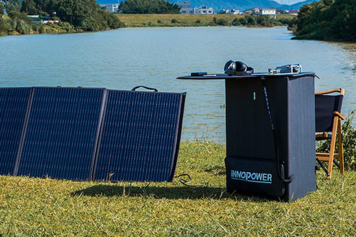 Ein Solarpanel mit einem zu einem Tisch eingeklappten anderen Panel und einem See im Hintergrund.