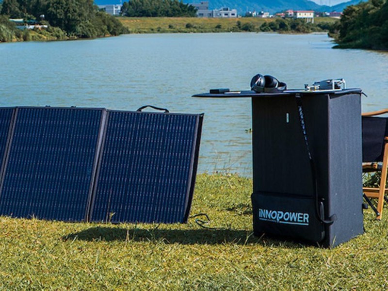 Ein Solarpanel mit einem zu einem Tisch eingeklappten anderen Panel und einem See im Hintergrund.