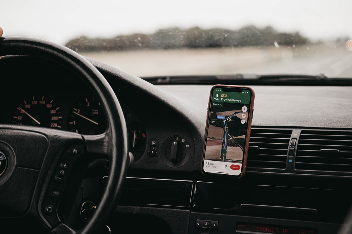 Ein Handy mit Google Maps an einem Armaturenbrett im Auto.