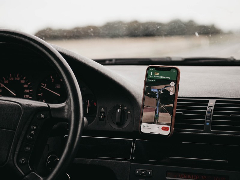 Ein Handy mit Google Maps an einem Armaturenbrett im Auto.