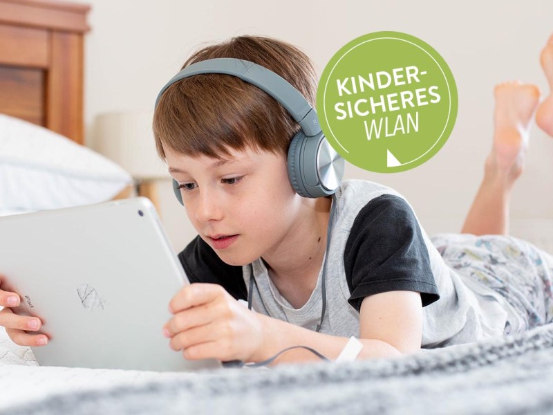 Kind liegt und sieht auf ein Tablet