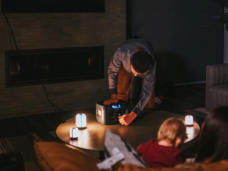 Eine Familie sitzt im Dunkeln und schließt an die BioLite Power Station Lampen an.