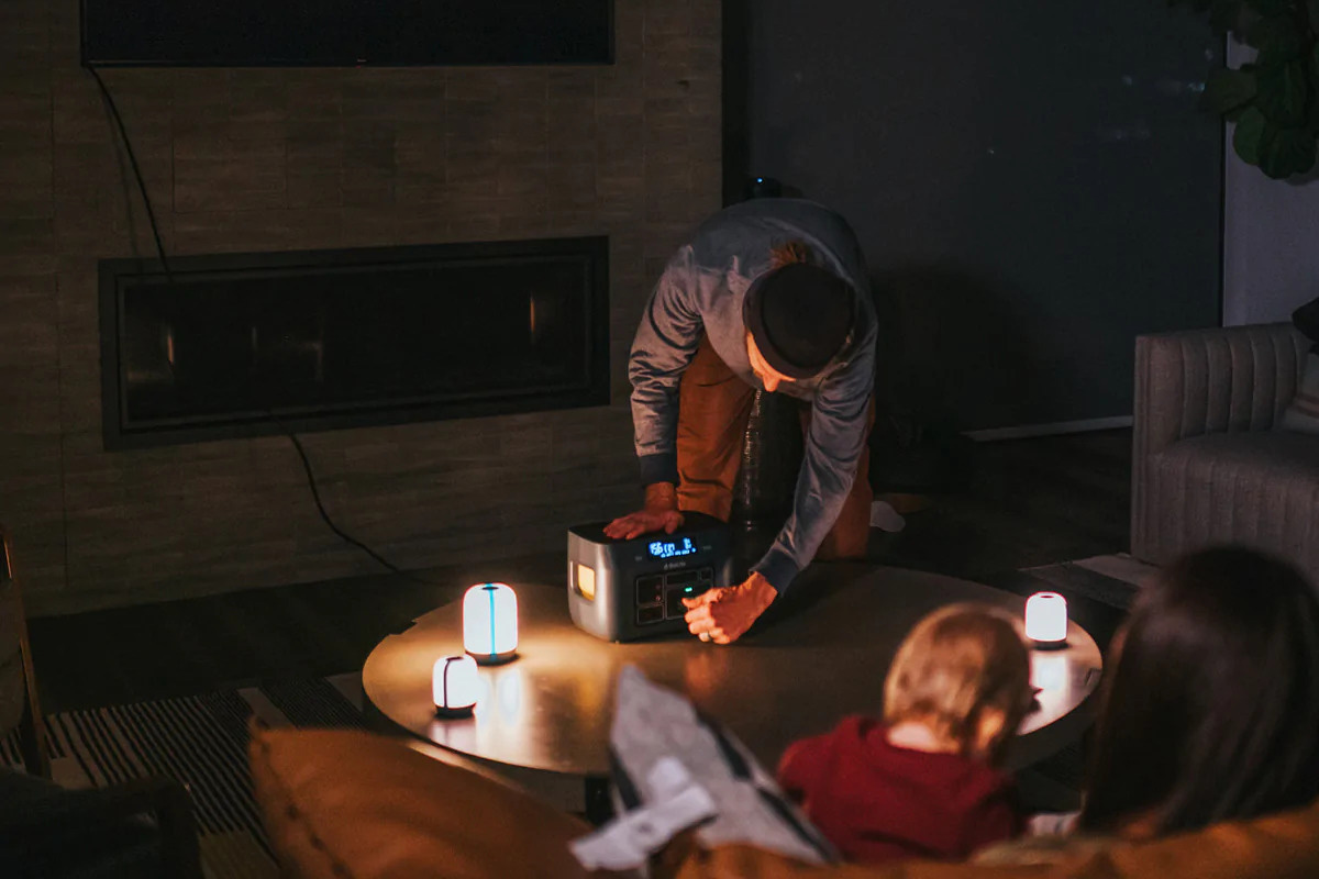 Eine Familie sitzt im Dunkeln und schließt an die BioLite Power Station Lampen an.