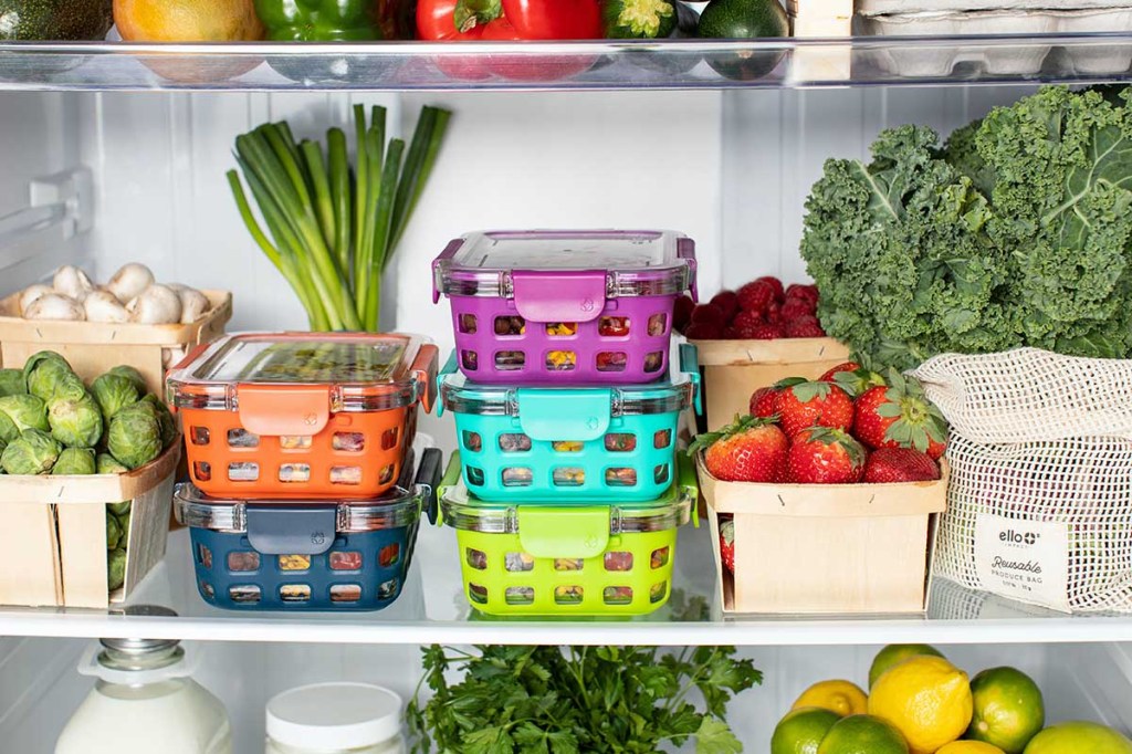 Ein Kühlschrank mit Gemüse, Obst und gefüllten Containern.