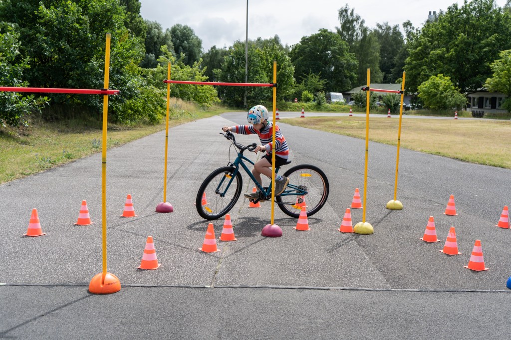 Kind fährt mit einem Fahrrad durch einen Slalomparcours