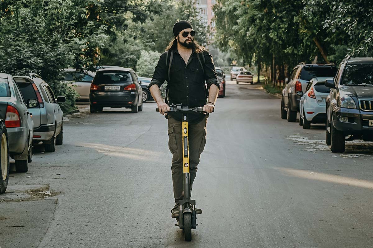 Eine Person fährt auf einem E-Scooter durch eine Stadt.