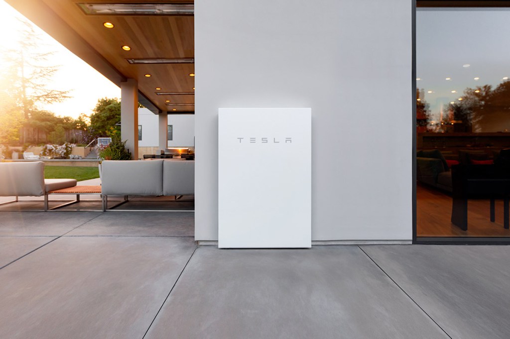 Die Tesla Powerwall - ein weißer Kasten - steht an einer Wand in einem Haus.