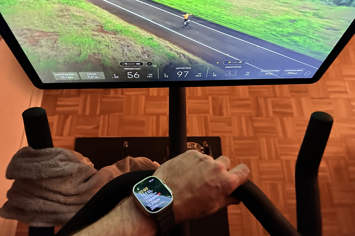Blick auf Arm mit Smartwatch der nach Lenker von Heimtrainer greift