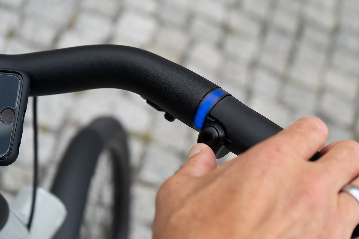 Finger drückt Boost-Knopf für mehr Tempo beim VanMof S5 City-E-Bike – Detailaufnahme.