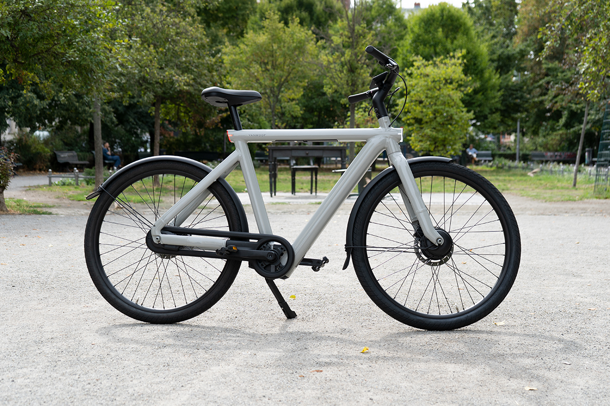 VanMoof S5 City-E-Bike steht in Seitenansicht vor eine Park.