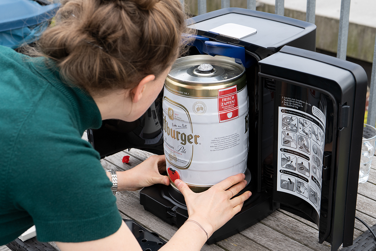 Eine Frau stellt ein Bierfass in die mobile Bierzapfanlage.