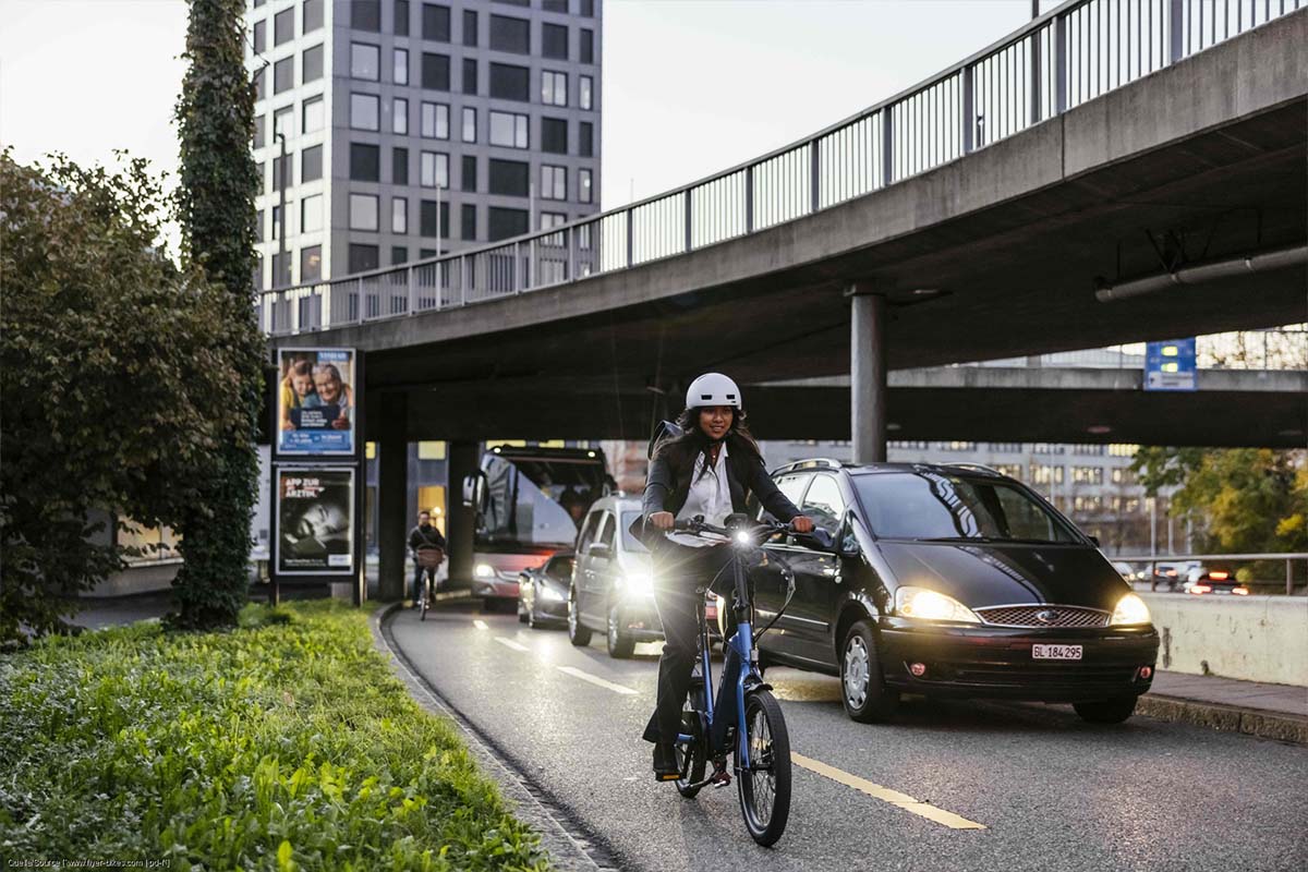 Frau fährt auf einem Fahrradstreifen neben Autos durch die Stadt