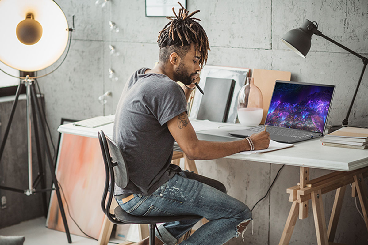 Ein Mann sitzt an einem Schreibtisch und arbeitet an einem Laptop.
