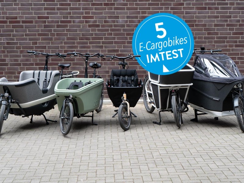 Fünf E-Cargobikes aufgereiht auf Pflastersteinen.