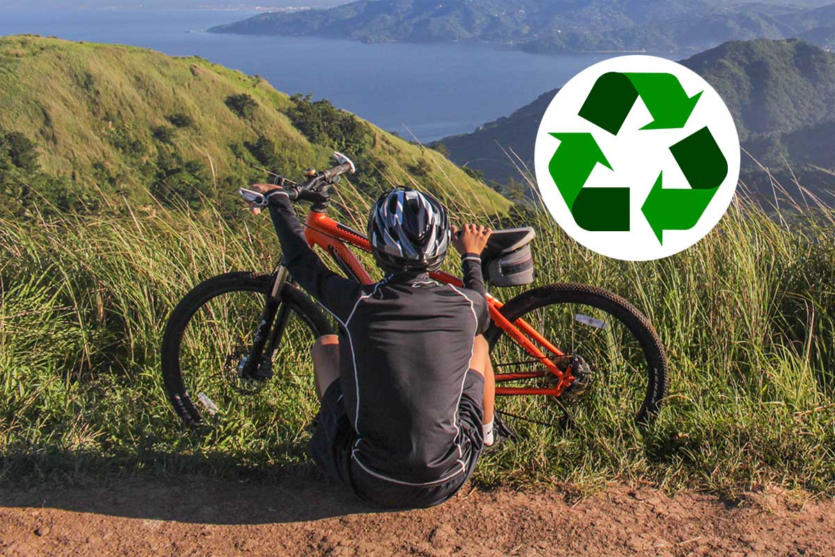 Mann sitzt vor seinem Fahrrad in der Natur, im Hintergrund ist ein See