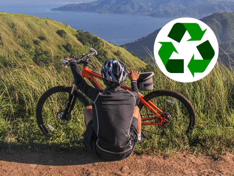 Mann sitzt vor seinem Fahrrad in der Natur, im Hintergrund ist ein See