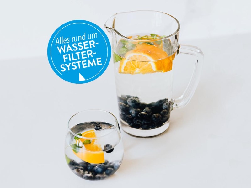 Glas und Karaffe auf weißem Tisch und Hintergrund.