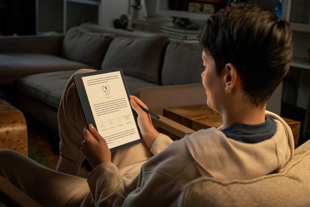 Eine Person sitzt auf dem Sofa und liest abends etwas auf dem Amazon Kindle Scribe.