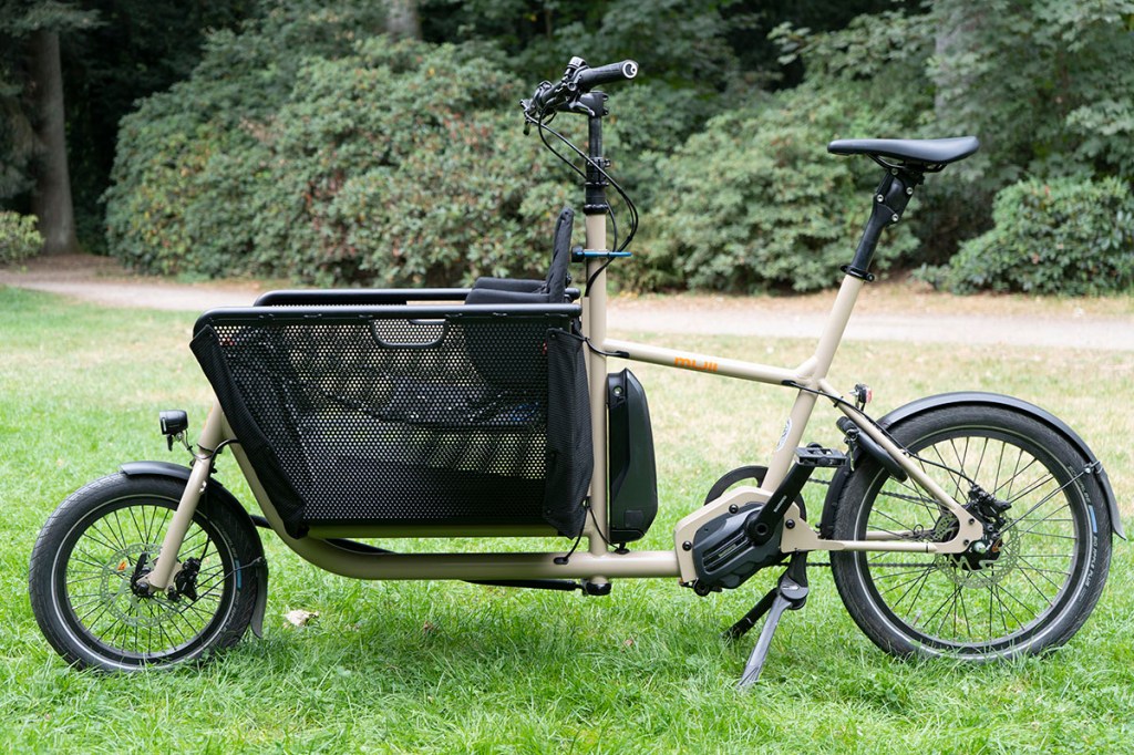 E-Cargo-Bike von Muli in Seitenansicht vor einem Park.