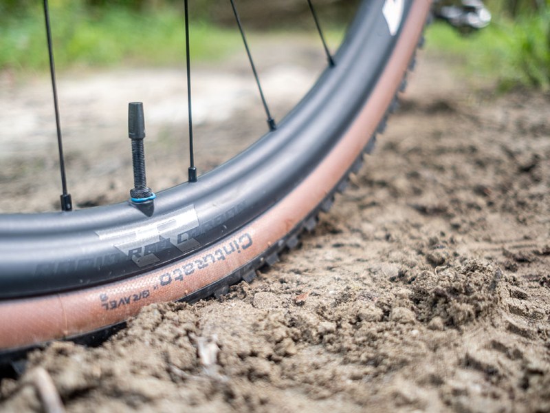Nahaufnahme eines Pirelli-Reifens für E-Gravel-Bikes bei einer Fahrt über unwegsamen Boden.