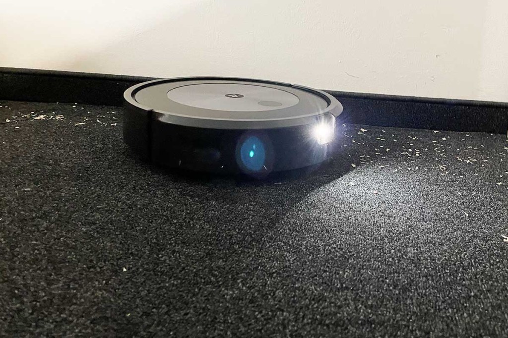 Der Roomba j7+ beim Saugen auf Teppich mit eingeschaltetem Licht.