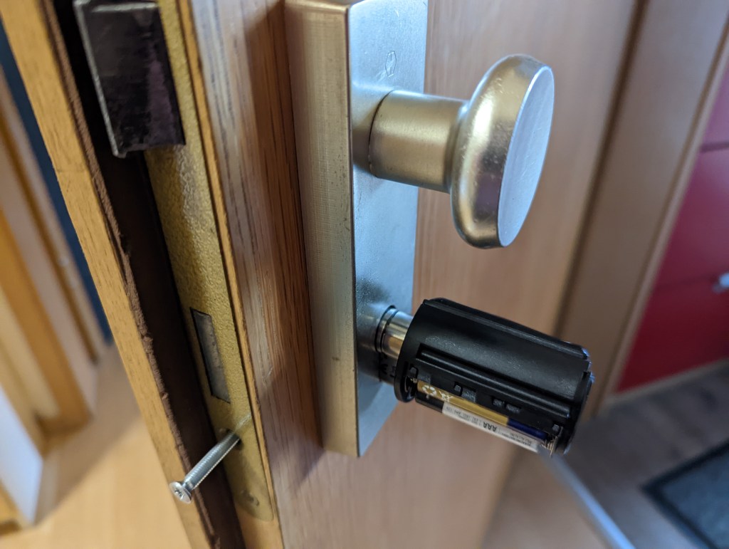 Das Welock Smat Lock in einer Tür montiert. Der Zylinder steht über den Schutzbeschlag über