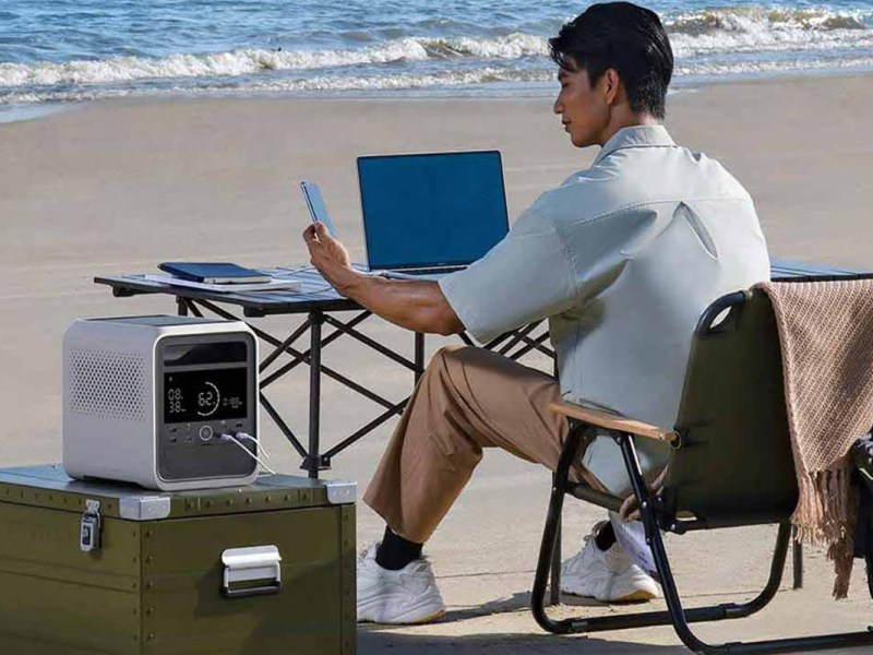 Eine Person arbeitet an einem Schreibtisch am Strand. Daneben steht die neue Xiaomi Mijia 1000 Pro Power Station.