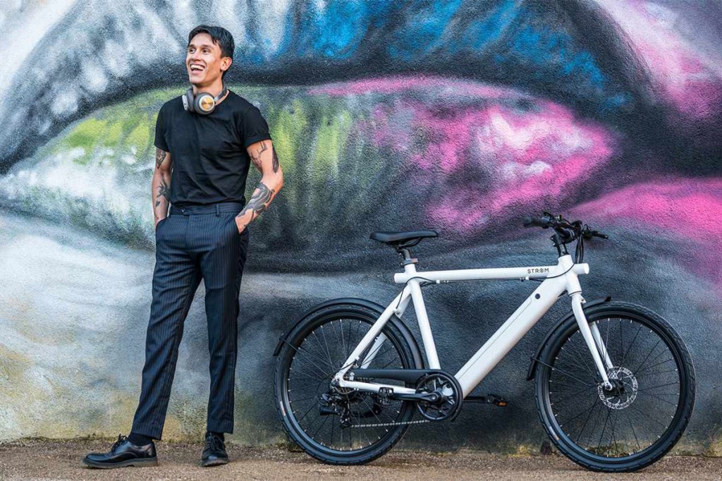 E-bike von Strøm vor einer Graffitiwand, daneben steht ein Mann