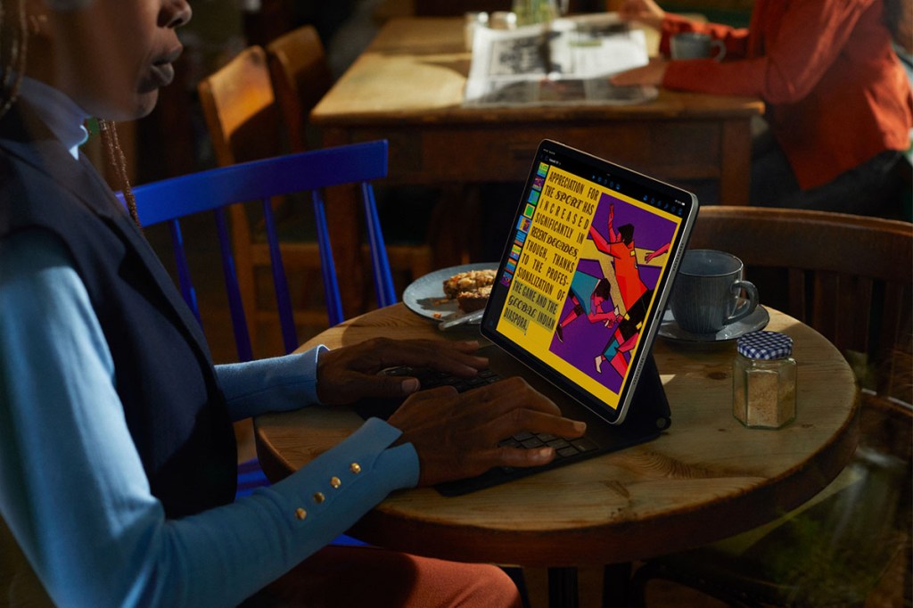 Mann sitz an einem Tisch und schreibt Texte über eine Ansteck-Tastatur eines iPads