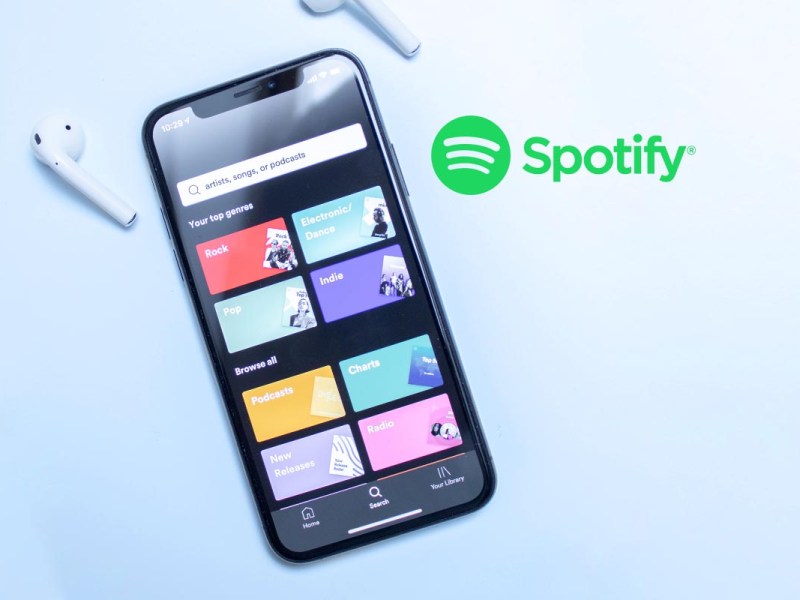 Ein Smartphone mit der Spotify App auf blauem Hintergrund