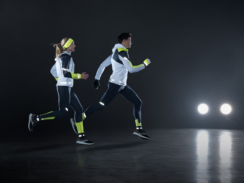 Zwei Personen laufen im Dunkeln. Sie tragen die neue Lauf-Kollektion von Brooks. Im Hintergrund sind Autoscheinwerfer zu sehen.
