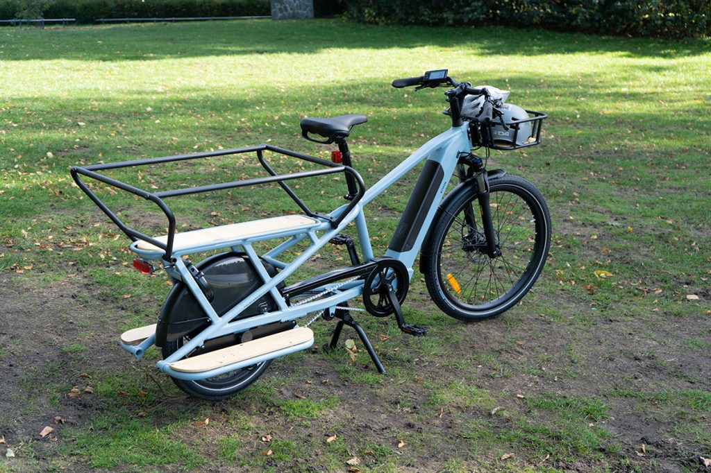 Decathlon Ecargobike R500E Longtail steht auf einer Wiese.