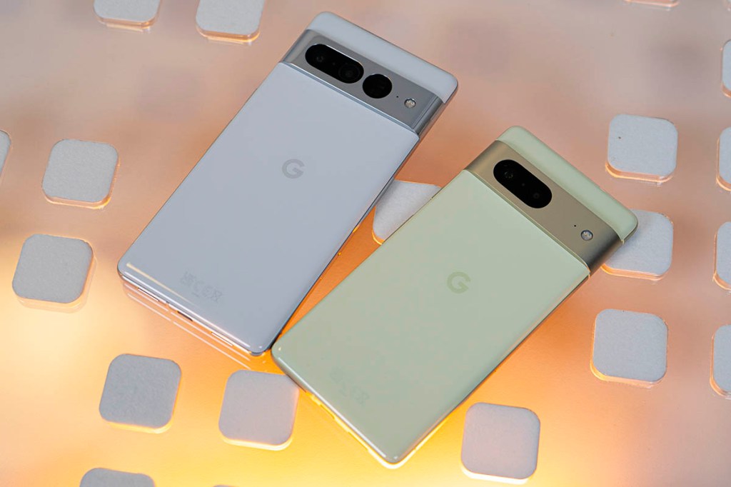 Google Pixel 7 und Pixel 7 Pro nebeneinander auf Glasplatte, gelblich hinterleuchtet