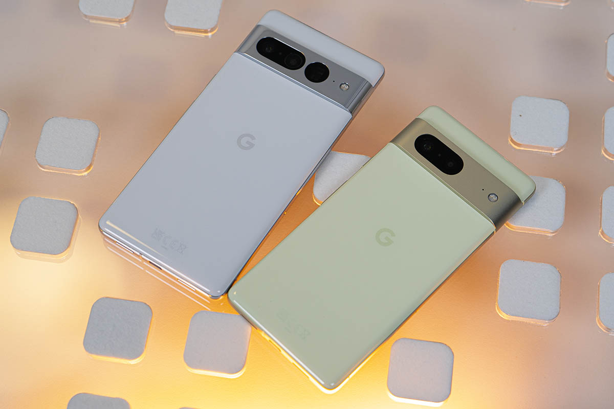 Google Pixel 7 und Pixel 7 Pro nebeneinander auf Glasplatte, gelblich hinterleuchtet
