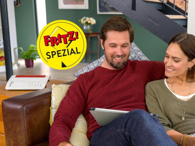 Mann und Frau sitzen auf dem Sofa mit Tablet in der Hand daneben steht eine FritzBox