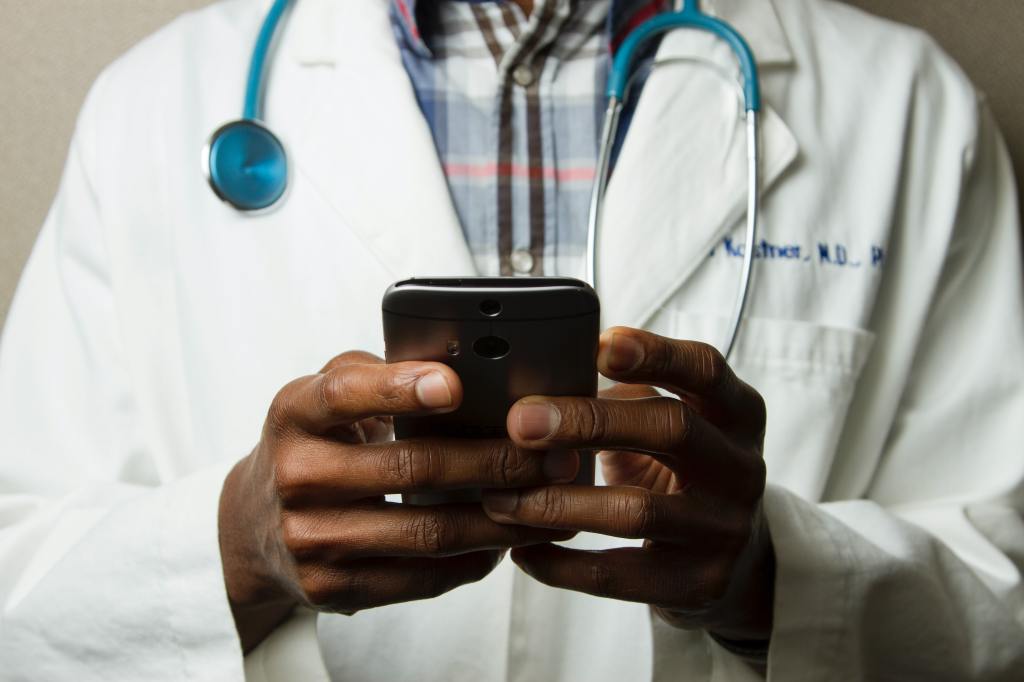 Arzt tippt auf Smartphone