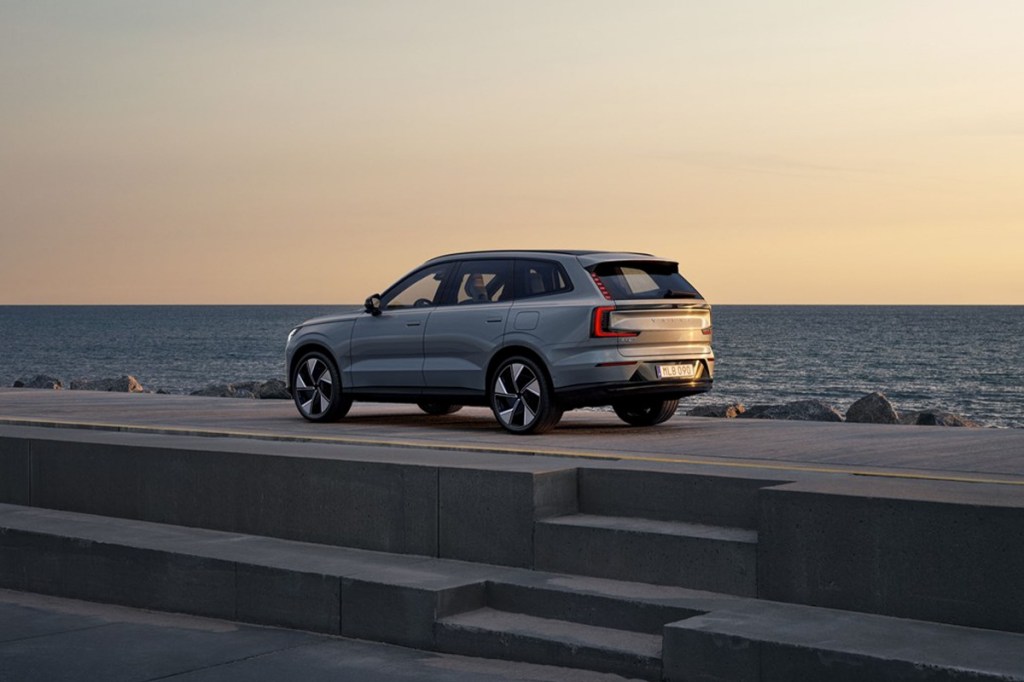Der Volvo EX90 steht auf einer Plattform und im Hintergrund sieht man Wasser.