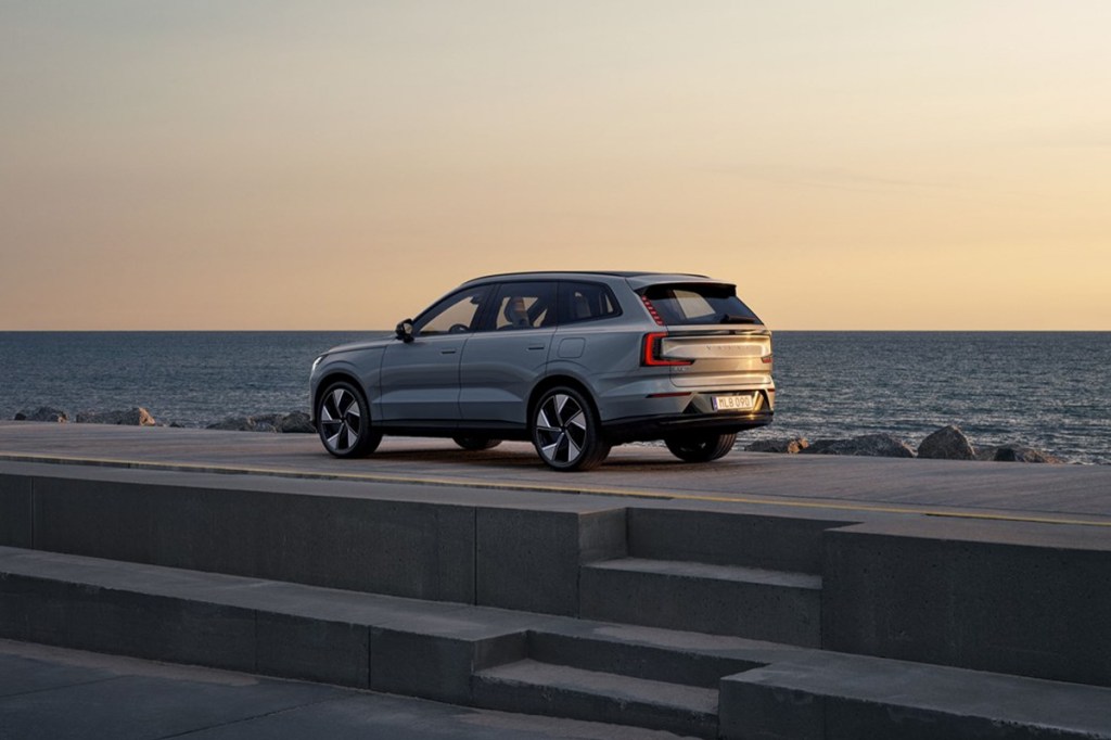 Der Volvo EX90 steht auf einer Plattform und im Hintergrund sieht man Wasser.