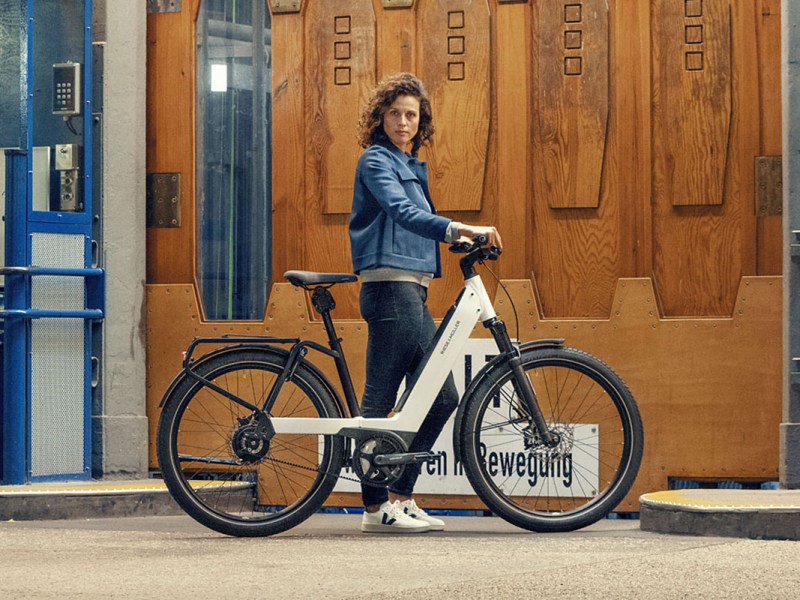 Frau schiebt Riese & Müller Nevo E-Bike durch ein Straße.