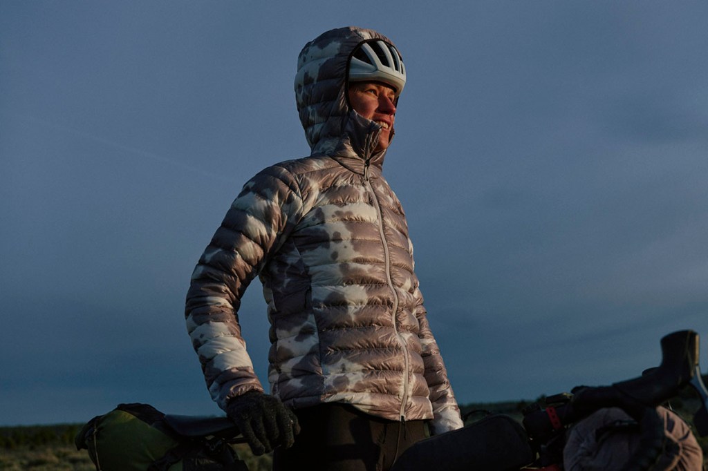 Frau mit Daunenjacke deren Kapuze über ihren Fahrradhelm gezogen ist.